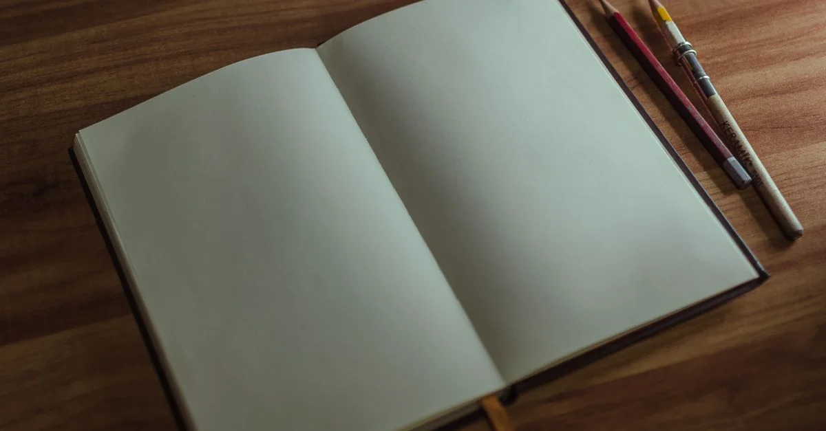 Un carnet de croquis ouvert avec des crayons sur un bureau en bois, parfait pour les artistes et les créatifs.