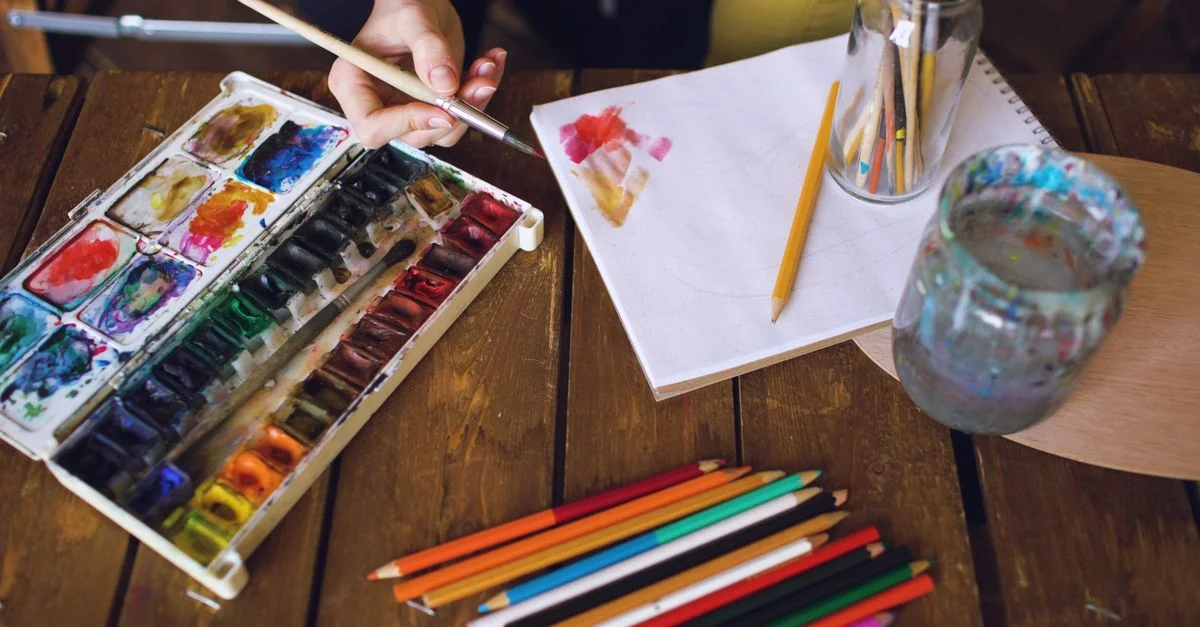 Un espace de travail vibrant d'artiste avec des aquarelles, des crayons et un carnet de croquis, prêt pour l'expression créative.