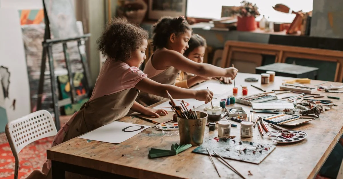 Trois jeunes filles s'adonnent à la peinture dans un studio d'art intérieur, explorant leur créativité.