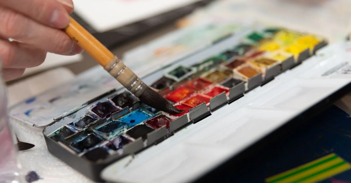 Vue détaillée de la main d'un artiste utilisant une palette d'aquarelle pour une peinture vibrante.